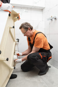 Installation d'un siphon par un plombier dans une douche pour éviter les mauvaises odeurs